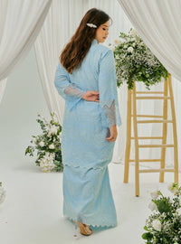 A woman dressed in Baby Blue Tun Farah Embroidered Eyelet Kurung