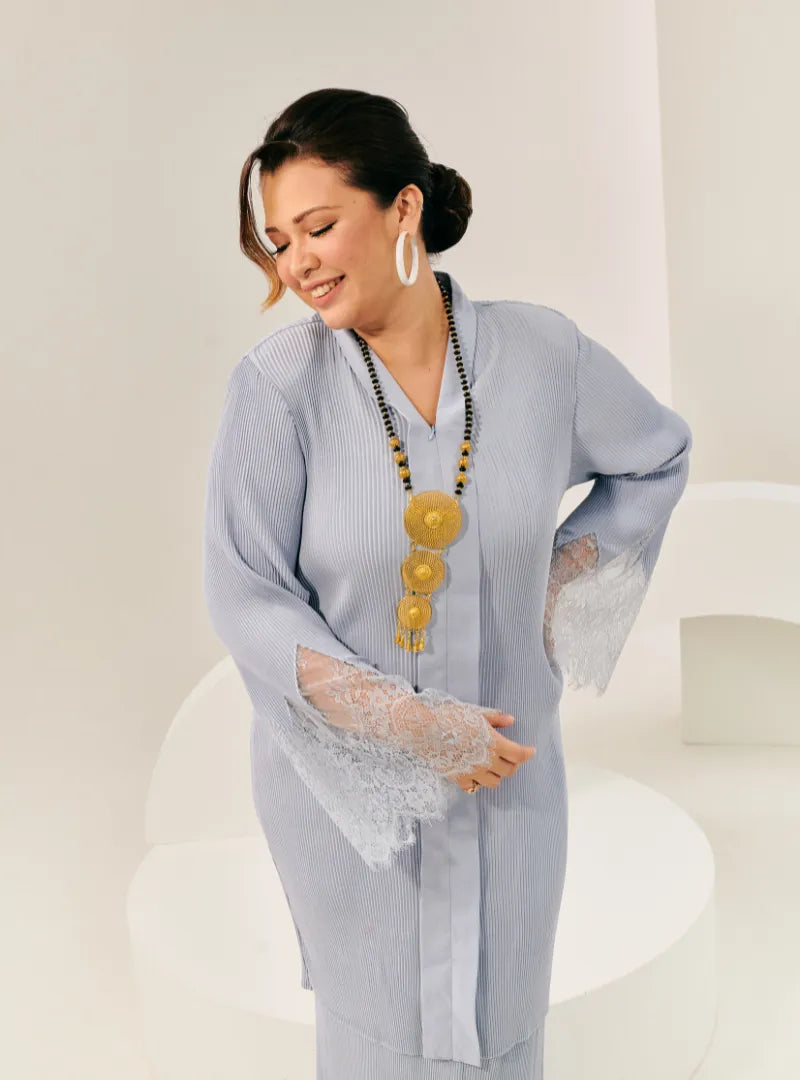 A woman dressed in Baby Blue Tun Jamilah Pleated Kurung