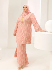 A woman dressed in Baby Salmon Tun Maryam Eyelet Kurung