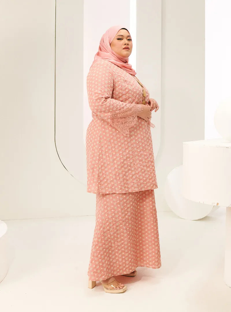 A woman dressed in Baby Salmon Tun Maryam Eyelet Kurung