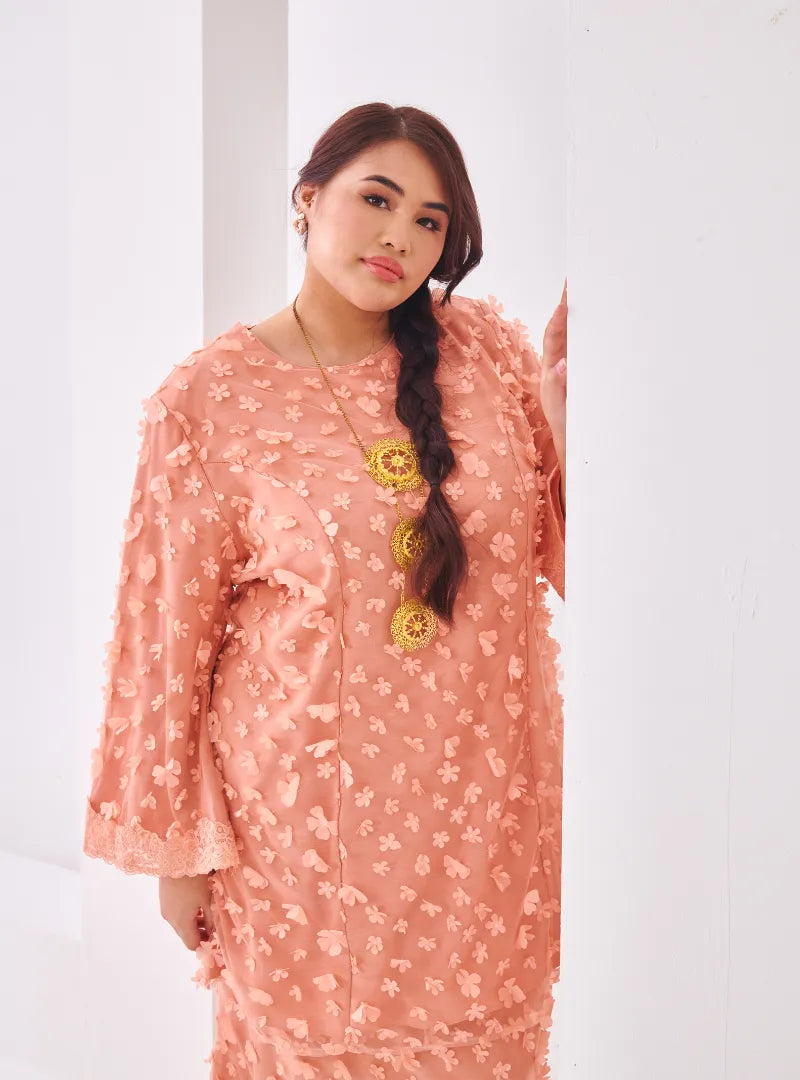 A woman dressed in Baby Salmon Tun Sharifah Lace Kurung