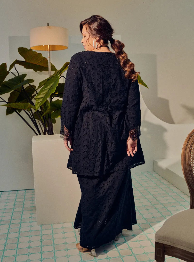 A woman dressed in Black Tun Huda Eyelet Kurung