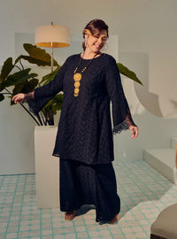 A woman dressed in Black Tun Huda Eyelet Kurung