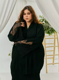 A woman dressed in Black Tun Jamilah Pleated Kurung