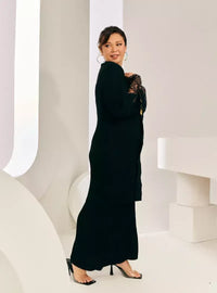 A woman dressed in Black Tun Jamilah Pleated Kurung