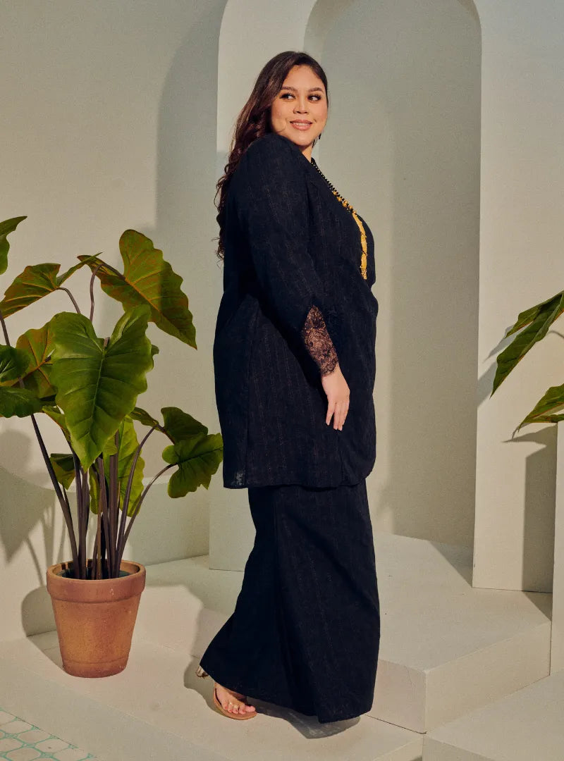 A woman dressed in Black Tun Kiambang Striped Cotton Lace Kurung