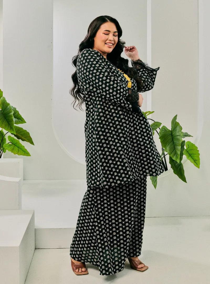 A woman dressed in Black Tun Maryam Eyelet Kurung