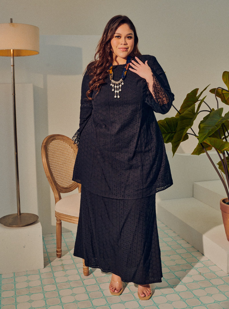 A woman dressed in Black Tun Rosmiza Eyelet Embroidered Patchwork Kurung