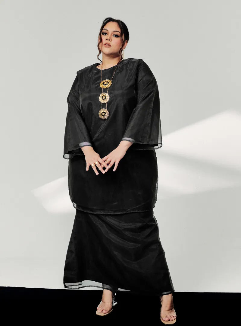 A woman dressed in Black Tun Sharimah Organza Kurung