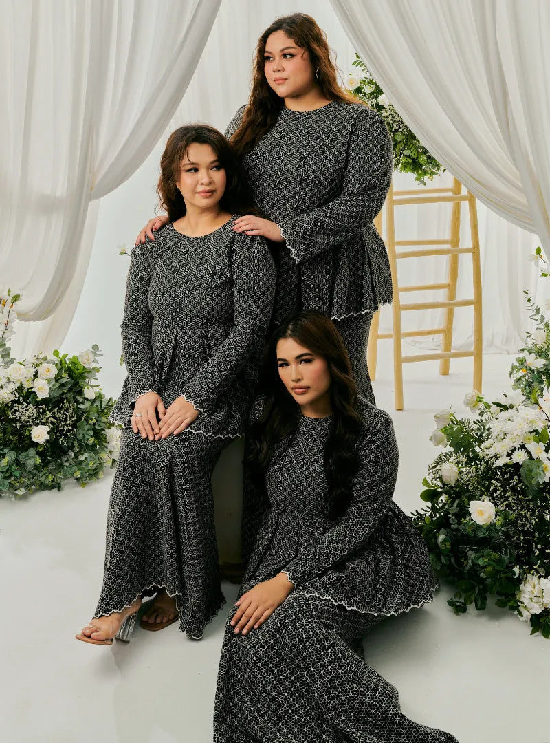 A woman dressed in Black Tun Zera Eyelet Kurung