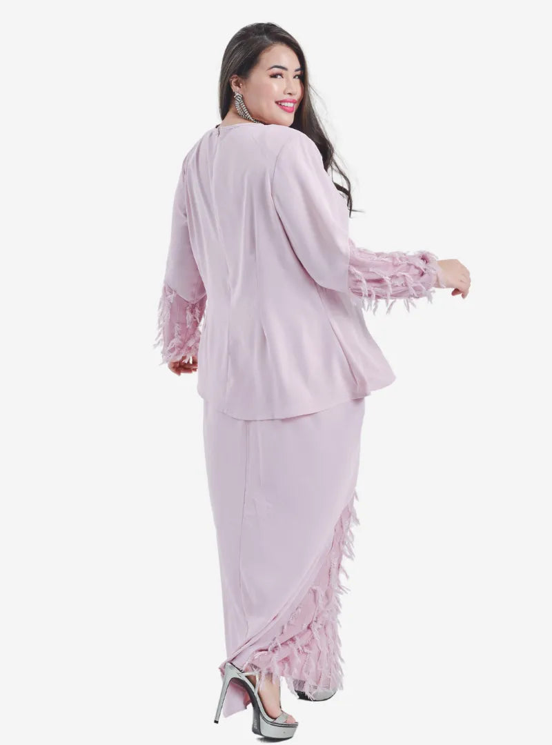 A woman dressed in Blush Pink Lalang Feather Kurung