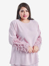 A woman dressed in Blush Pink Lalang Feather Kurung