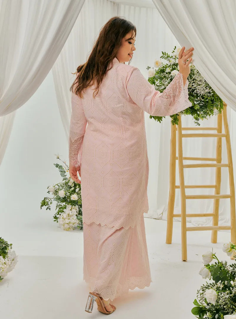 A woman dressed in Blush Pink Tun Farah Embroidered Eyelet Kurung