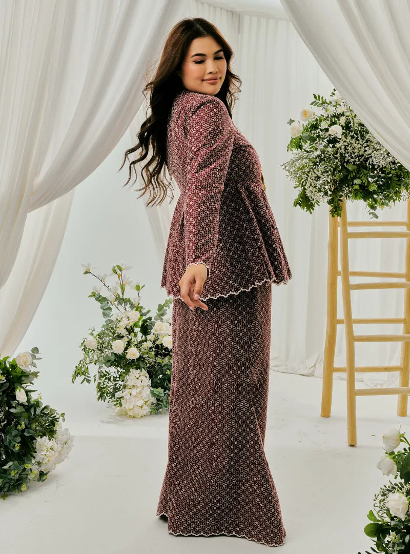 A woman dressed in Burgundy Tun Zera Eyelet Kurung