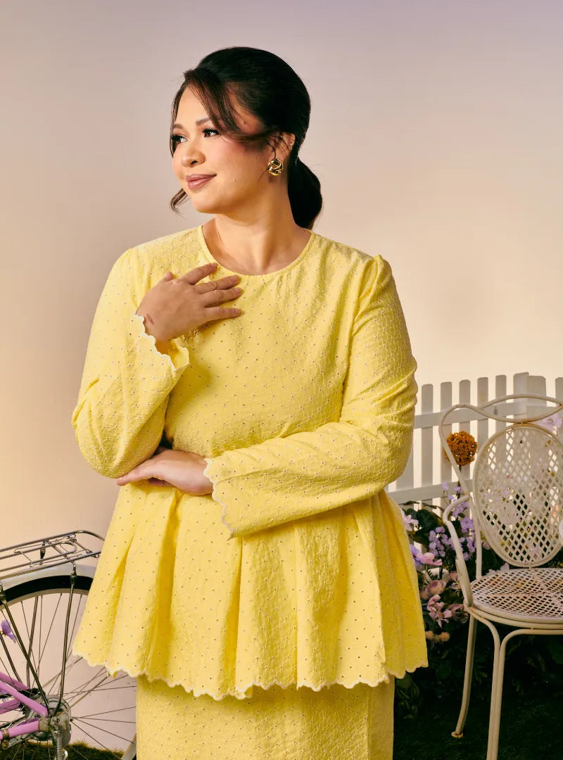 A woman dressed in Buttermilk Tun Zera Eyelet Kurung