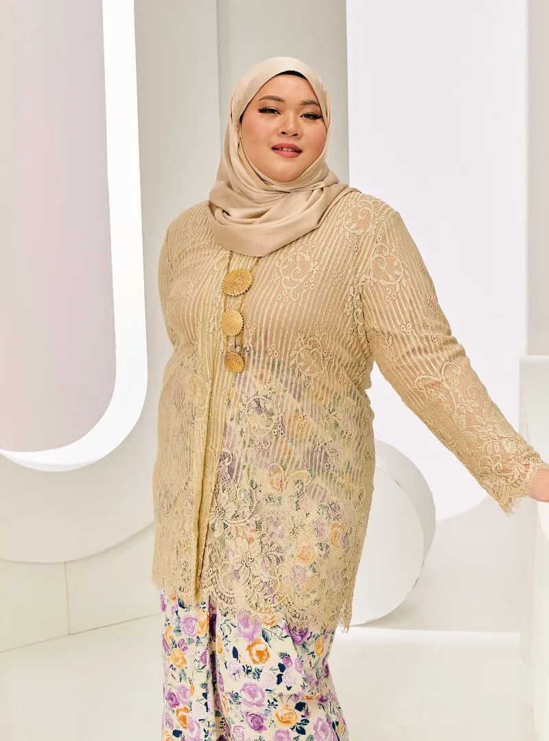 A woman dressed in Champagne Tun Basirah Kebaya Lace Nyonya