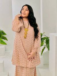 A woman dressed in Champagne Tun Huda Eyelet Kurung