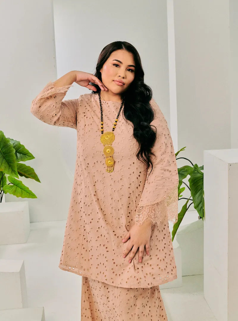 A woman dressed in Champagne Tun Huda Eyelet Kurung