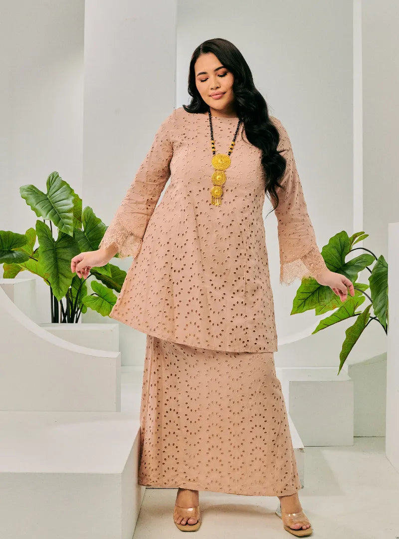 A woman dressed in Champagne Tun Huda Eyelet Kurung