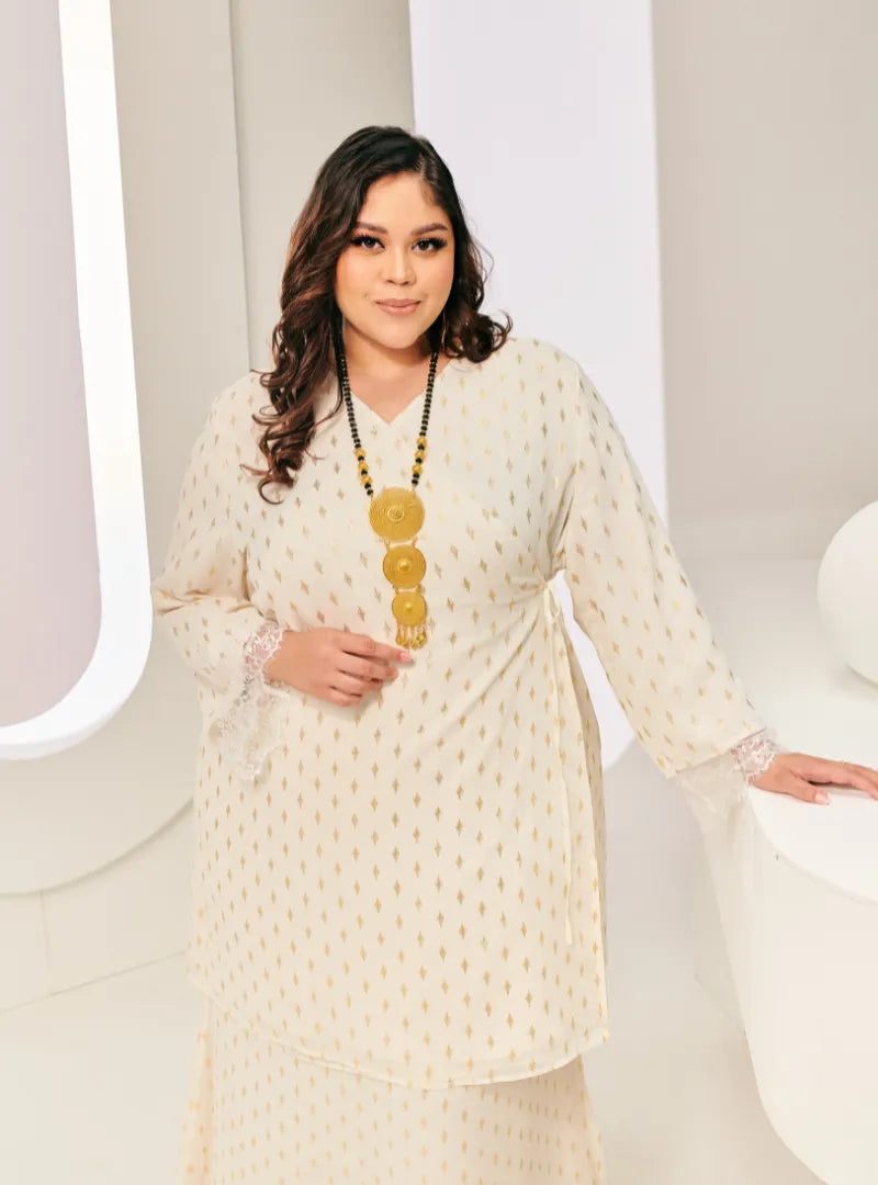 A woman dressed in Champagne Tun Tipah Dotted Wrap Kurung