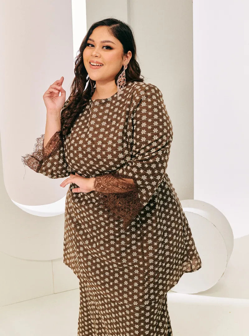 A woman dressed in Chocolate Tun Maryam Eyelet Kurung