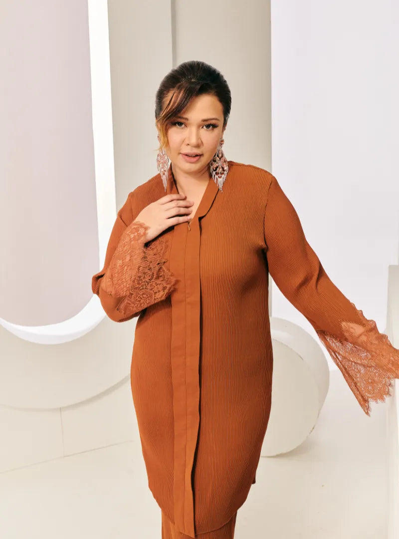 A woman dressed in Cinnamon Tun Jamilah Pleated Kurung