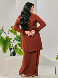 A woman dressed in Cinnamon Tun Malika Feather Wrap Kurung