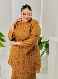 A woman dressed in Coffee Tun Huda Eyelet Kurung