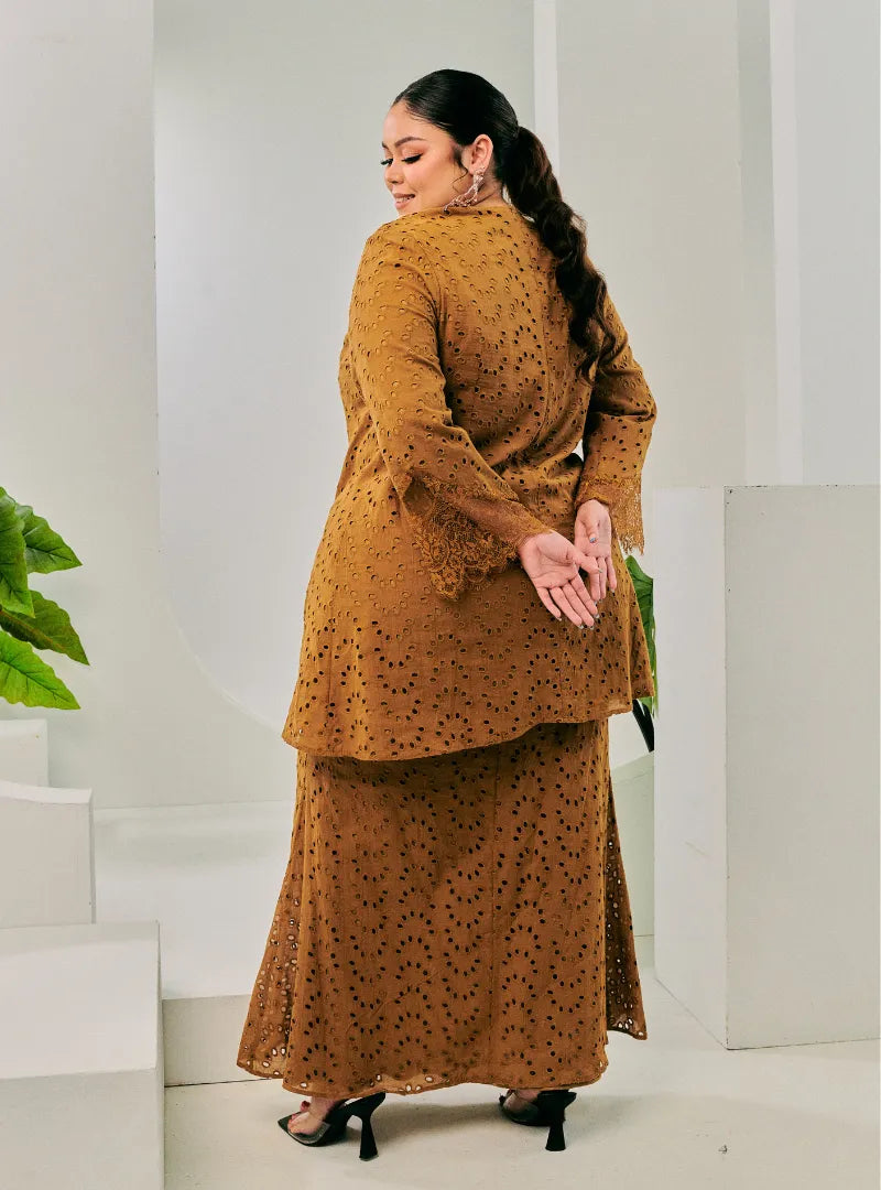 A woman dressed in Coffee Tun Huda Eyelet Kurung