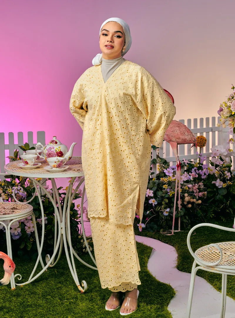 A woman dressed in Creamy Corn Tun Yasmin Eyelet Oversized Kurung