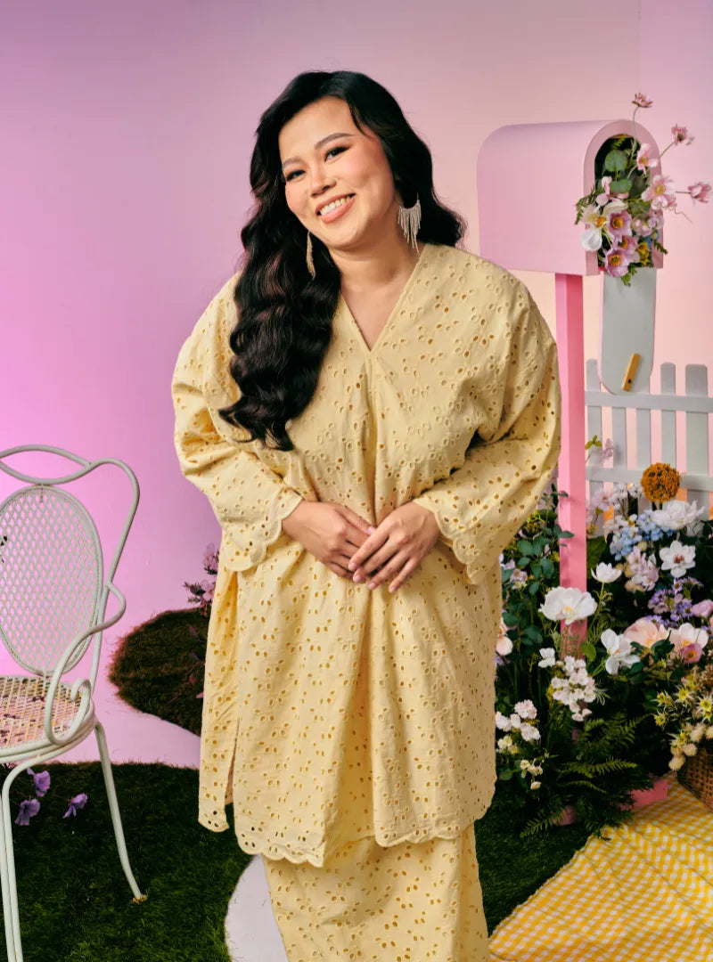 A woman dressed in Creamy Corn Tun Yasmin Eyelet Oversized Kurung