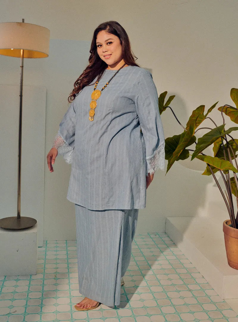 A woman dressed in Dusty Blue Tun Kiambang Striped Cotton Lace Kurung