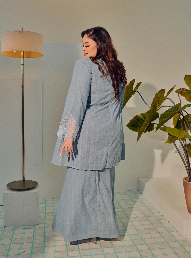 A woman dressed in Dusty Blue Tun Kiambang Striped Cotton Lace Kurung