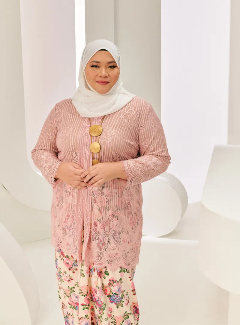 A woman dressed in Dusty Pink Tun Basirah Kebaya Lace Nyonya
