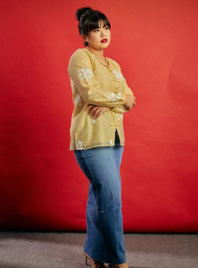 A woman dressed in Egg Nog Wong Gu Embroidered Cheongsam Top