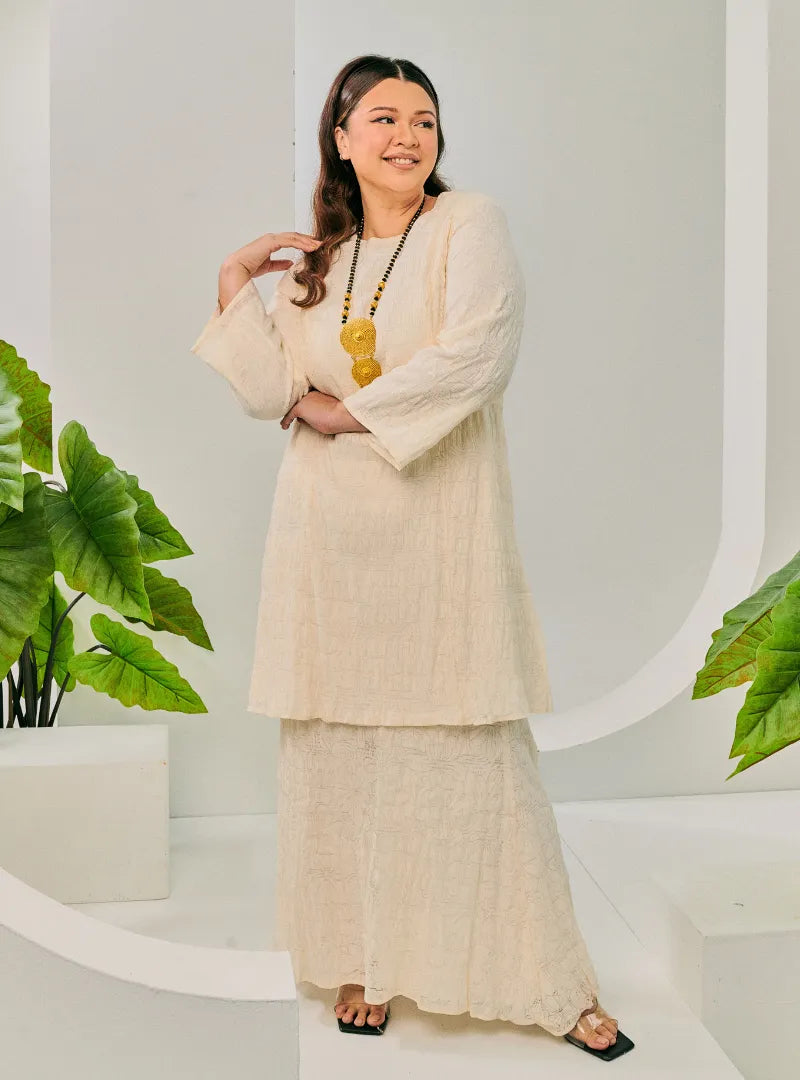 A woman dressed in Egg White Tun Bibah Textured Kurung