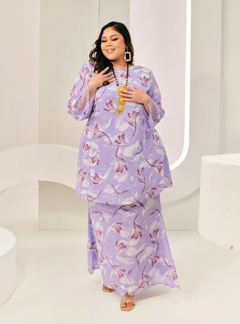 A woman dressed in Lilac Flower Tun Rokiah Printed Kurung Pahang