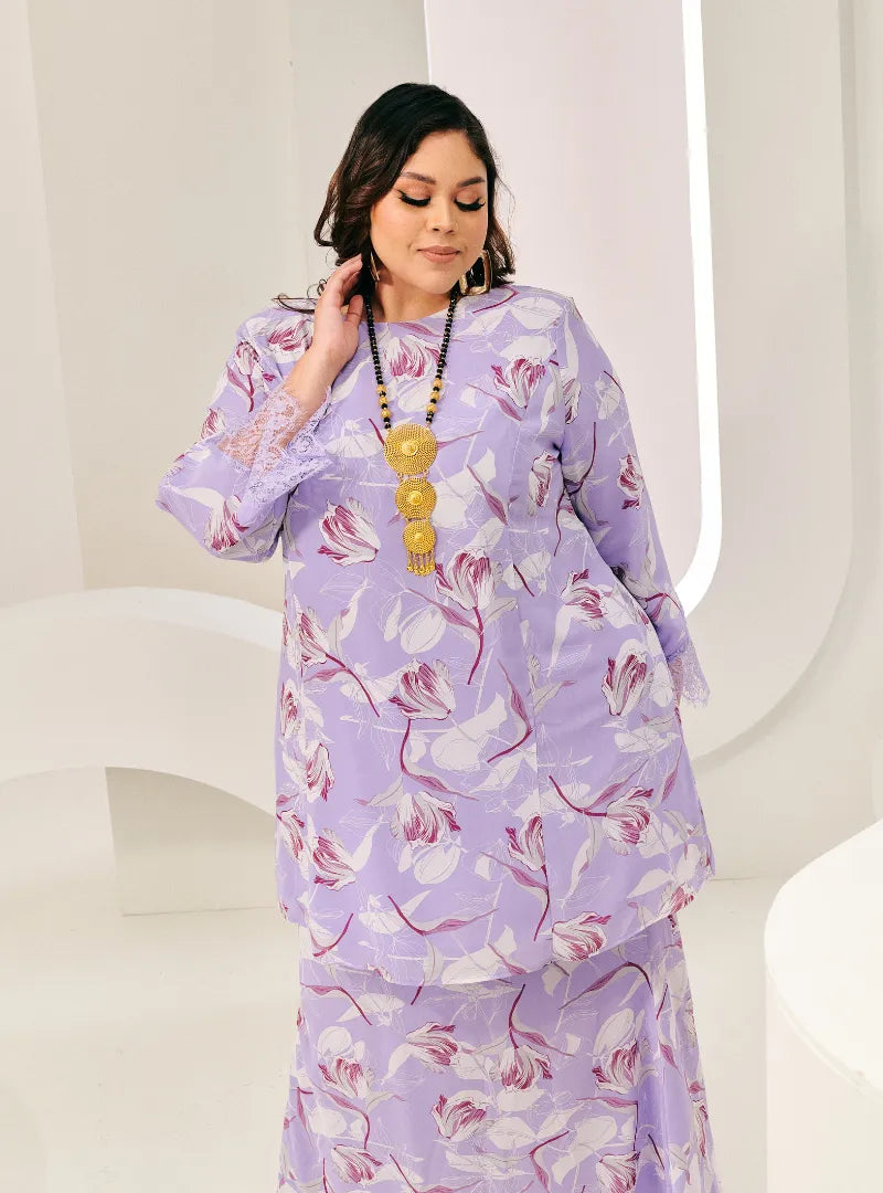 A woman dressed in Lilac Flower Tun Rokiah Printed Kurung Pahang