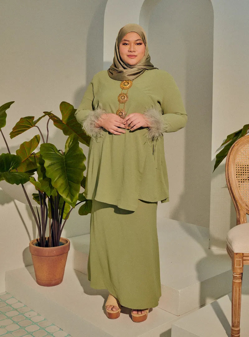 A woman dressed in Mint Green Tun Malika Feather Wrap Kurung