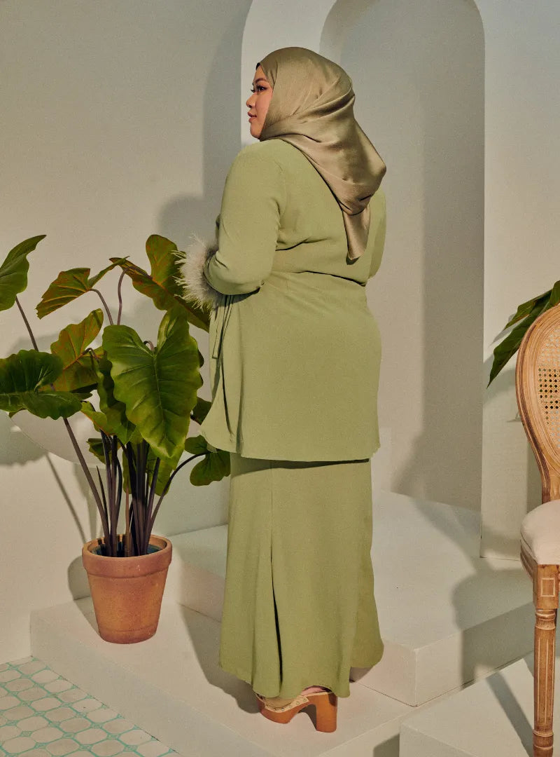 A woman dressed in Mint Green Tun Malika Feather Wrap Kurung