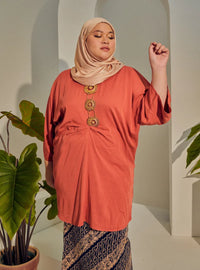 A woman dressed in Orange Tun Bedah Top