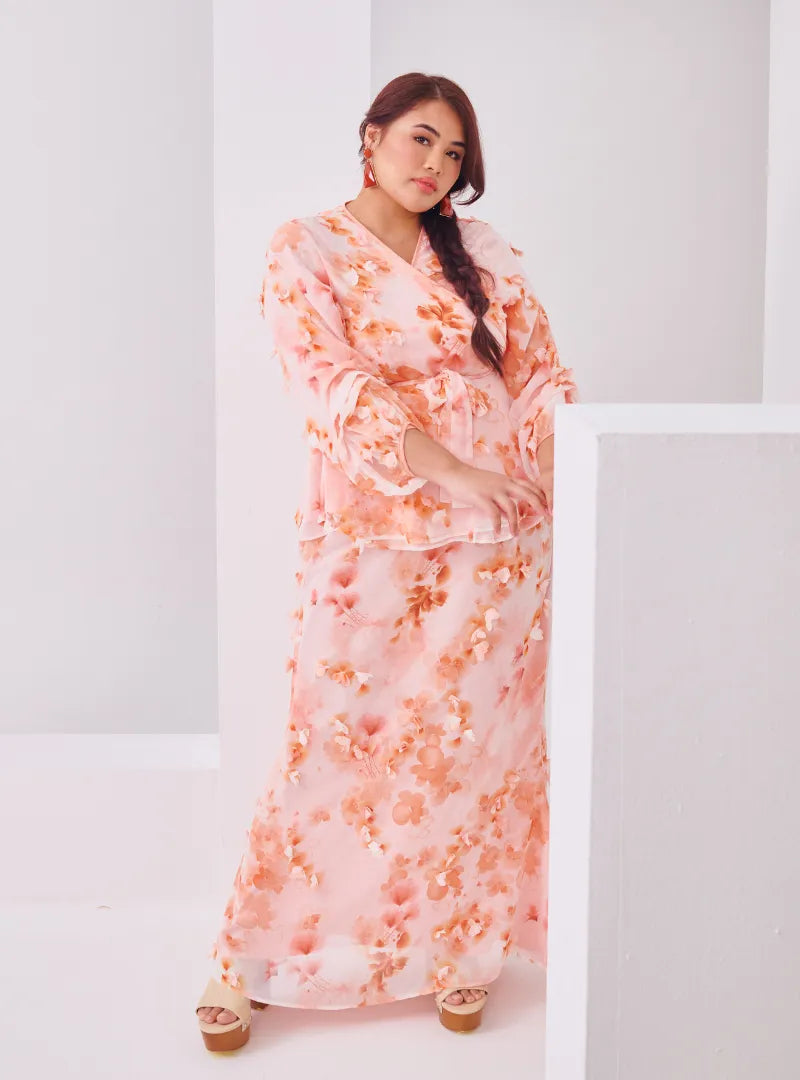 A woman dressed in Peach Tun Hamidah Chiffon Wrap Kurung