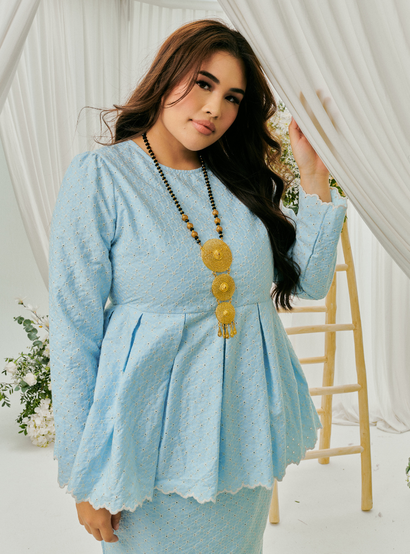 A woman dressed in Powder Blue Tun Zera Eyelet Kurung