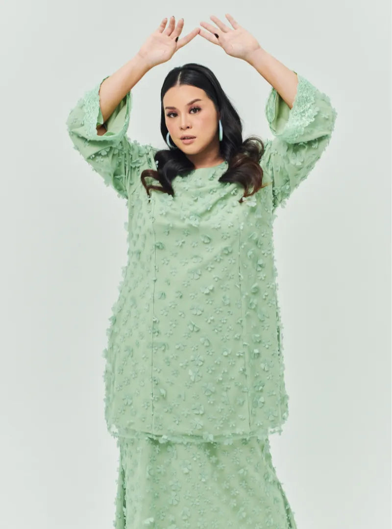 A woman dressed in Sage Green Tun Sharifah Lace Kurung