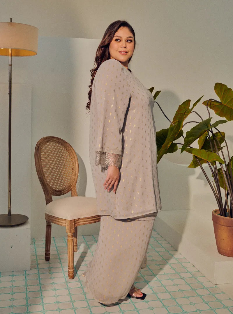 A woman dressed in Silver Grey Tun Tipah Dotted Wrap Kurung