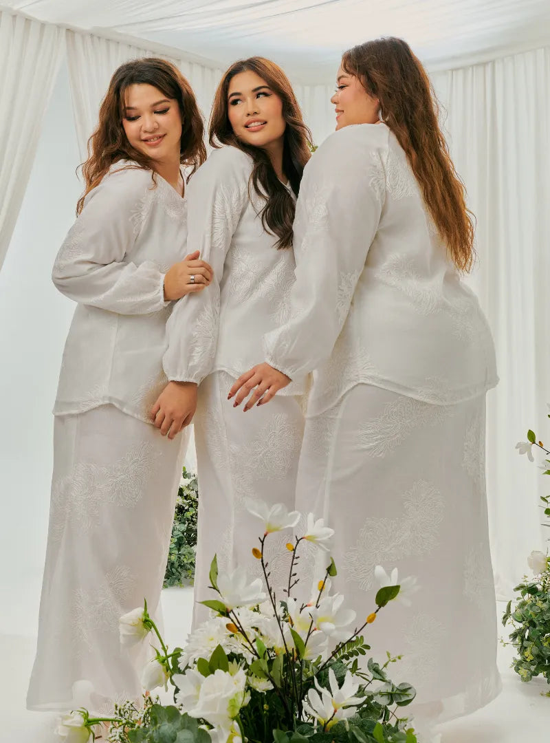 A woman dressed in White Tun Iman Mandarin Kurung